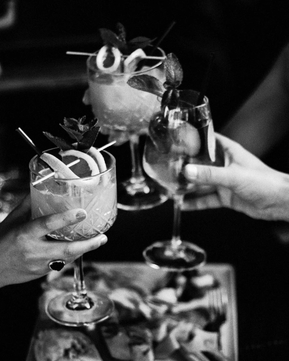 Guests clink garnished cocktails.
