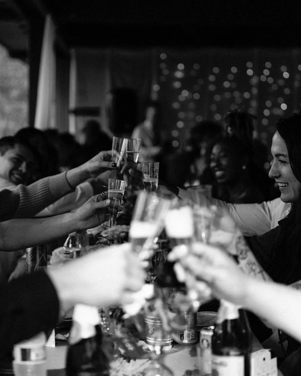 A crowd of guests toasts across a long table.