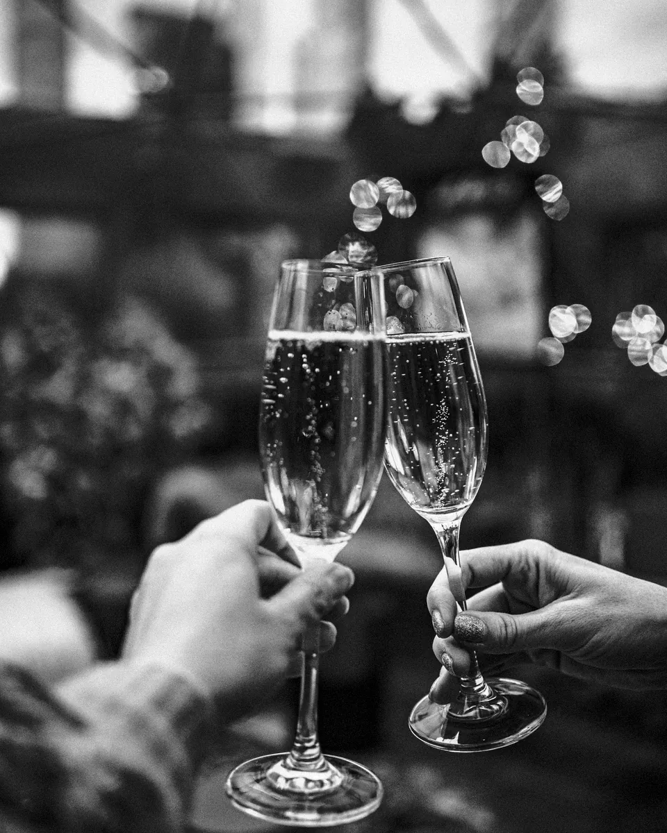 Two champagne flutes touch under soft lights.