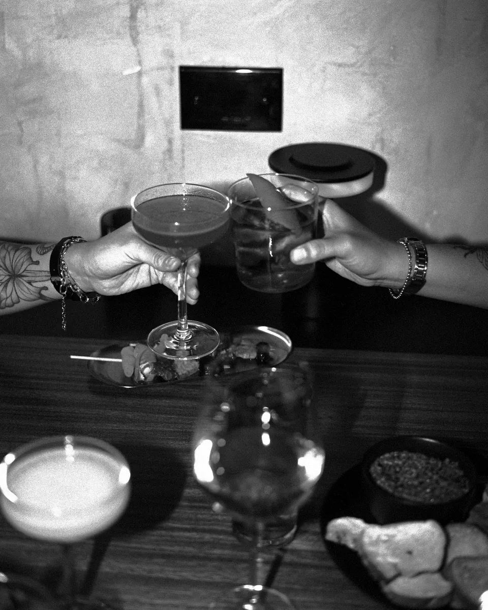 Drinks handed across a table between guests.