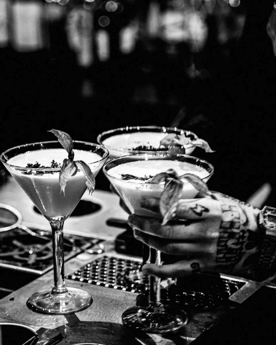 A row of martinis finished with fresh herbs.