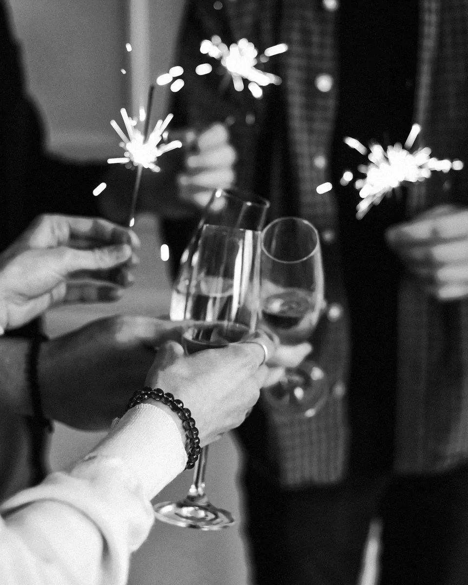 Guests raise glasses among lit sparklers.