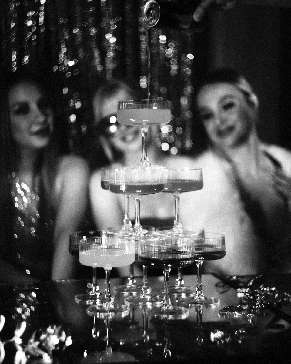 A champagne tower is poured at a party.
