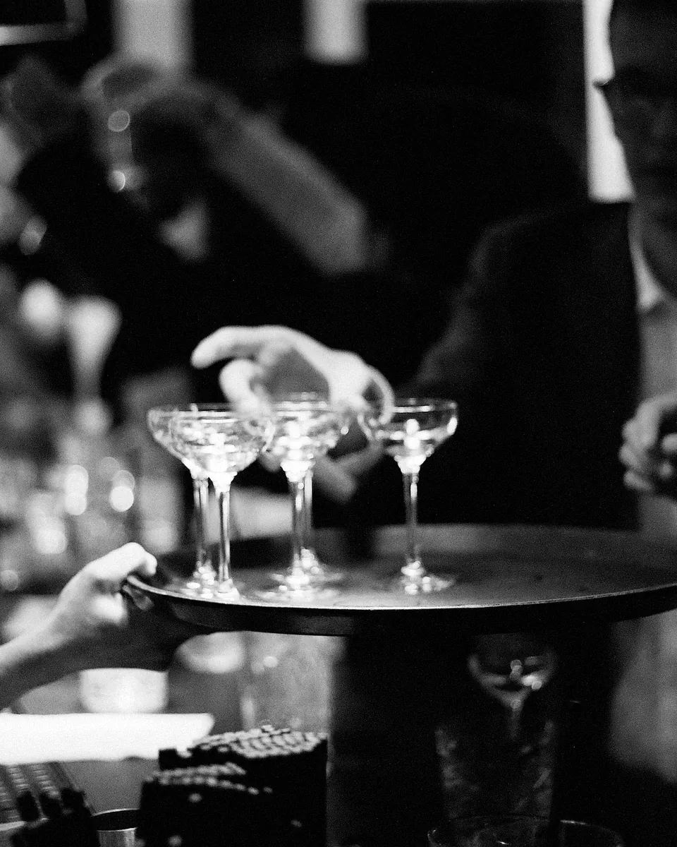 A guest takes a coupe from a tray of fresh drinks.